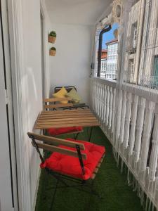 a table and a red chair on a balcony at Apartamento casco viejo in Ourense +4 photos