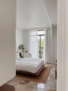 a white bedroom with a bed and a window at BeLam in Hue Villa in Hue