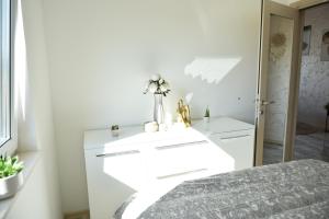 a white bedroom with a bed and a vase of flowers at pappy home in Pasuljište