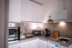 a kitchen with white cabinets and a sink and a microwave at Apartman Georgijev with private Free parking in Zlatibor