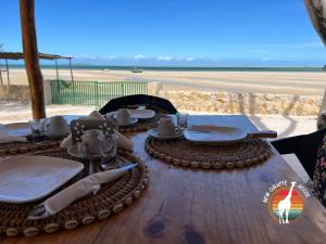 a wooden table with plates and utensils on top of the beach at New Giraffe House in Vilanculos