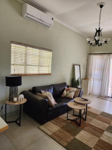 a living room with a black couch and two tables at Eros Weg Family Flat in Windhoek