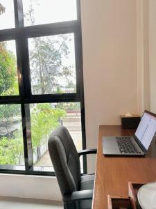 a desk with a laptop and a chair next to a window at Koze Suites in Dumaguete