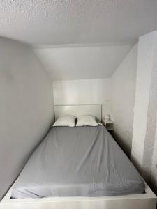 a large bed in a white room with avertisementatronatronstrationstration at Collioure, bel appartement de 40m2 avec balcon et parking in Collioure