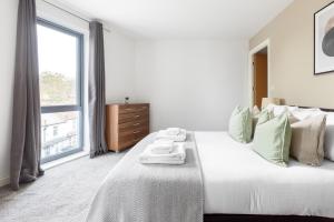 een slaapkamer met een groot wit bed en handdoeken bij The Colindale Collection in Colindale