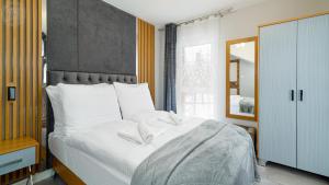 a bedroom with a bed with white sheets and a mirror at Apartamenty Good Time - Hugo Apartments - blisko centrum in Szklarska Poręba