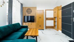 a living room with a green couch and a tv at Apartamenty Good Time - Hugo Apartments - blisko centrum in Szklarska Poręba