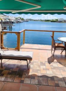 - une terrasse avec 2 chaises, une table et de l'eau dans l'établissement Beautiful 2BR and 2 en-suite bathroom with Marina and Sunset views, à Jolly Harbour