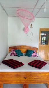 Una cama con dos almohadas y un globo rosa encima. en Tree Cool Resort en Ella