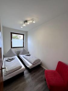 グリンデにあるModerne gemütliche Wohnung in Glindeのベッド2台と赤いソファが備わる客室です。