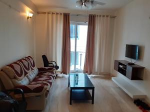 a living room with a couch and a table and a tv at Ixora Suites in Bangalore