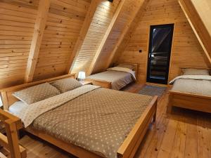 two beds in a room with wooden walls at A Jahorina in Jahorina