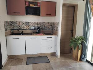 uma cozinha com armários brancos e um lavatório em Studio en campagne em Avignon