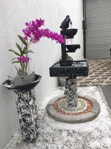 two vases with flowers and a bird in a fountain at White Rooms by Sineth in Ratmalana