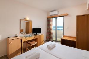 ein Hotelzimmer mit einem Bett und einem Schreibtisch mit einem Spiegel in der Unterkunft Nafsika Hotel in Rhodos (Stadt)