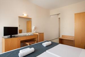 a bedroom with a bed and a desk with a television at Nafsika Hotel in Rhodes Town