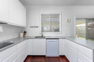 een witte keuken met een spoelbak en een vaatwasser bij 100 Paces in Broadwater +9 foto's