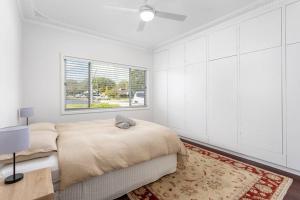 een witte slaapkamer met een bed en een raam bij 100 Paces in Broadwater