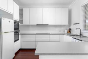 een witte keuken met witte kasten en een spoelbak bij 100 Paces in Broadwater