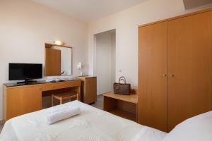 a bedroom with a bed and a dresser with a television at Nafsika Hotel in Rhodes Town