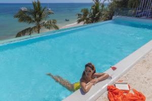 a woman sitting in a swimming pool next to the beach at HM Bavaro Beach - Adults Only in Punta Cana