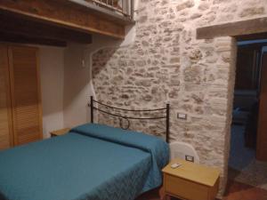 1 dormitorio con cama y pared de piedra en Casa vacanze Borgo medievale, en Porzano