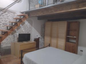1 dormitorio con 1 cama y escalera con TV en Casa vacanze Borgo medievale, en Porzano