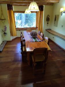 Un comedor con una gran mesa y sillas de madera. en Casa de La Montaña, en Villa La Angostura