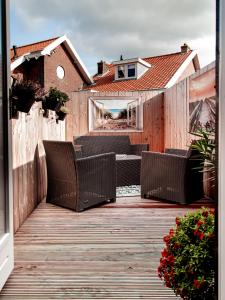 une terrasse en bois avec des chaises en osier dans l'établissement M&M Studio's 1 & 2, à Zandvoort