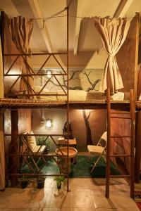 a room with bunk beds with chairs and tables at Happiness Community Wake & Bake Hostel - Rooftop Bar & Bistro in Pattaya