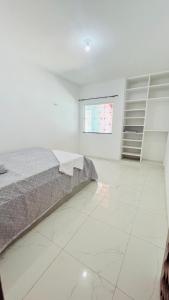um quarto com uma cama e piso em azulejo branco em Oásis da Praia em Caucaia