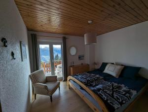 a bedroom with a bed and a chair and a window at Chalet Cactus - 4 Vallées in Hérémence
