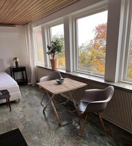 a room with a table and two chairs and two windows at Sea view nordic design apartment near beach great for couples in Snekkersten