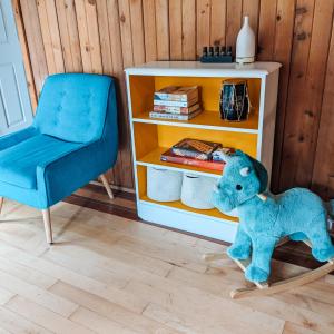 um bicho de peluche azul sentado numa cadeira ao lado de uma estante de livros em Nettledown Farms Bed & Breakfast em Salt Spring Island