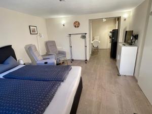 a bedroom with a bed and two chairs and a television at Ferienwohnung Eulenloch in Nördlingen
