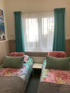 a room with two beds and a window with green curtains at Riposo in West-Terschelling