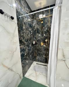 ein Bad mit einer Marmordusche mit einem Duschvorhang in der Unterkunft Premium Exclusive Suite in Nowy Dwór Mazowiecki