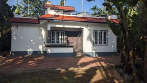 une maison blanche avec un toit rouge dans l'établissement Paddy View Service Villa, à Wayanad