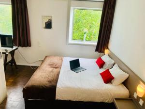1 dormitorio con 1 cama con ordenador portátil en Standing Hotel Suites by Actisource, en Roissy-en-France