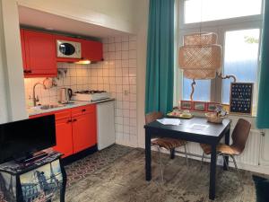 een keuken met rode kasten en een tafel met stoelen bij Riposo in West-Terschelling