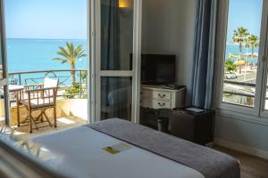 a bedroom with a bed and a balcony with the ocean at Hôtel du Bord de Mer "Le Vanillé" in Cagnes-sur-Mer