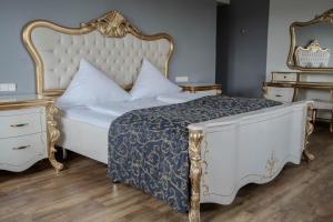 a bedroom with a white bed with a gold frame at Eventlocation & Hotel Schloss Neuburg in Obrigheim