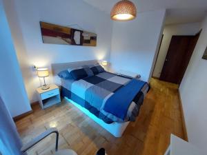 a bedroom with a blue bed and a lamp at Tiviti playa ribadesella in Ribadesella