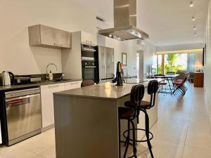 a kitchen with a counter and chairs in a room at A Beachfront Haven - Ocean Point B2 in Pointe aux Piments