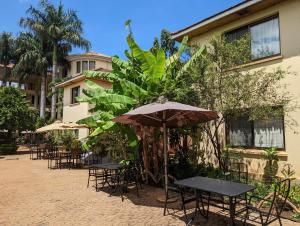 a patio with tables and chairs and an umbrella at Parkview Inn in Moshi