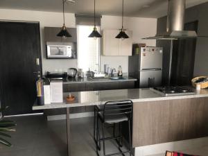 a kitchen with a counter with a stove and a refrigerator at Departamento exclusivo de lujo jardín y terraza gh3 in Guadalajara