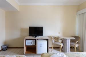 a living room with a tv and a table and chairs at Flat Costa Mar in Recife