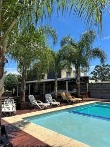 a swimming pool with lounge chairs and palm trees at Fuente de vida in Colón