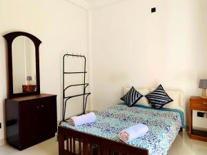 a bedroom with a bed with a dresser and a mirror at Villa Avi - Near Airport in Negombo