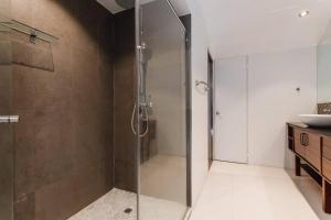 y baño con ducha y puerta de cristal. en Casa Azul - Apartamento de 2 Pisos, 2Hab con Rooftop en Casco Antiguo, en Panamá